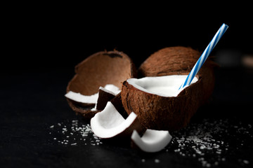 natural fresh coconut milkshake on a dark black background, milk in a plate of coconut