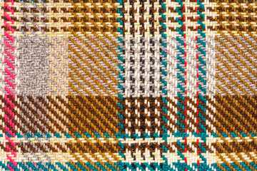 Brown checkered fabric with colored threads. Scottish wool. Fabric for plaid coat and suit. Close-up. Background