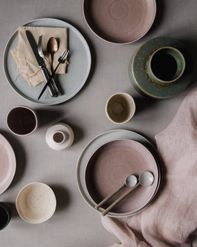 Flatlay von Keramiktellern und Tassen und Vasen und L&ouml;ffeln, der Tisch wird gedeckt