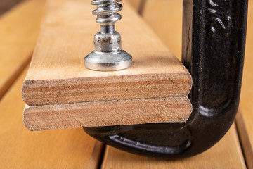 Metal wood clamp on a workshop table. Carpentry accessories in a wood workshop.