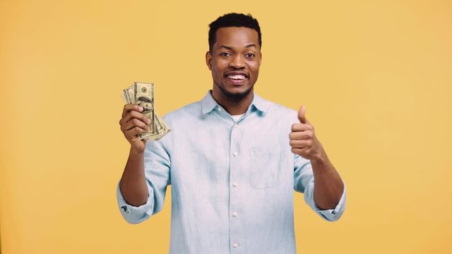 happy african american man counting money isolated on yellow