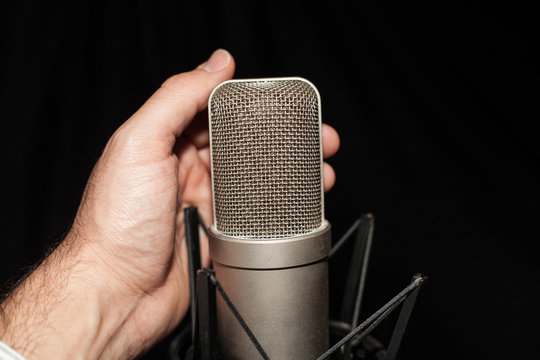 Cantando con microfono de studio en fondo negro