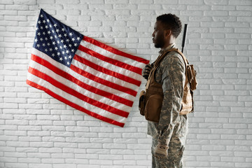 Fototapeta premium Side view of American soldier near national flag.