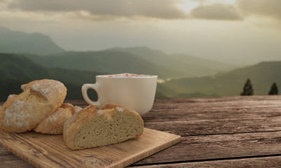 home made bread and  butcher in breakfast  concept on wooden table. Blur latte art coffee with chocolate sauce and caramel sauce  on Milk foam in white cup. Background mountian view and sunrise. 3D re