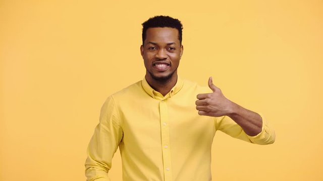 happy african american man showing thumb up isolated on yellow