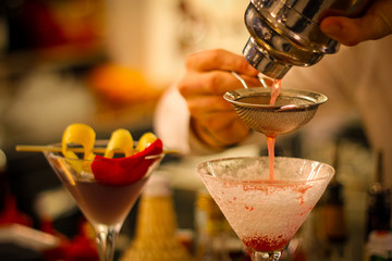 preparation with mixer and colander of cocktails with gin, egg white, lemon juice, granadina and icing sugar. Cocktail with vodka, lemon juice, grenadine, blue Curacao, Cointreau - 309275613