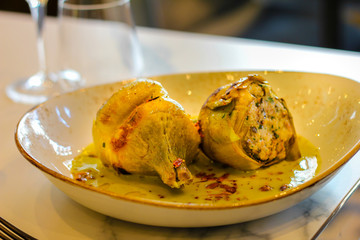 two stuffed artichokes in a dish with cream and chilli in a sophisticated Italian restaurant - 309275846