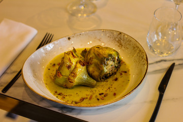 table set with plate and two stuffed artichokes with cream and chilli in a sophisticated Italian restaurant