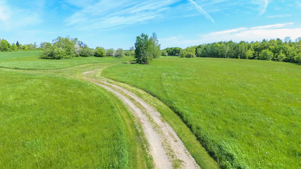 Aerial view of green field and dirt road
