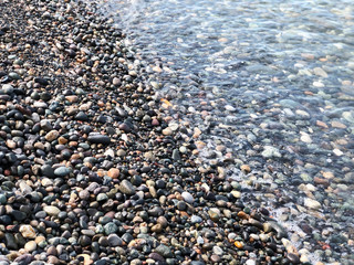 Close up view on beautiful stone beach of the sea. Summer sunny day, blue sky, water background