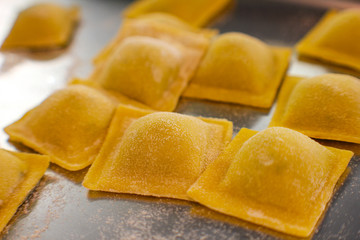 detail of raw spinach and ricotta ravioli on metal table with flour