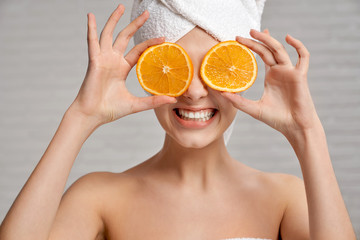 Happy woman after shower posing with fresh oranges