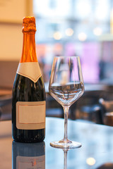 champagne bottle with blank labels on reflective table near an empty glass in a restaurant lights - 309277216