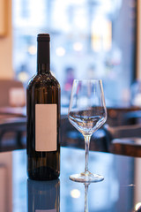 bottle of wine with empty labels on reflective table, with near a glass of wine in restaurant - 309277223