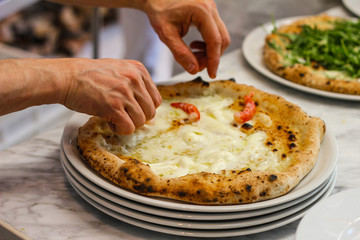 pizzaiolo garnish a pizza with shrimp in a typical Italian pizzeria