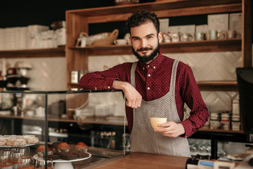 Positive barista standing behind counter