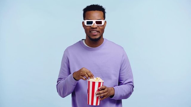 smiling african american man watching movie isolated on blue