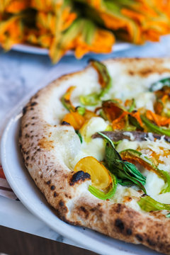 detail of a pizza with zucchini flowers, fresh mozzarella cetara anchovies, parmesan cheese and yellow tomatoes of Vesuvius