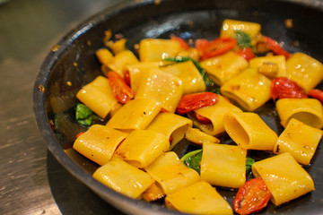 pan with handmade paccheri pasta and sautéed aubergines, citrus-flavored confit cherry tomatoes and spotted red in fine Italian restaurant