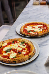 two margherita pizzas freshly baked on the pizzaiolo's work table - 309278236