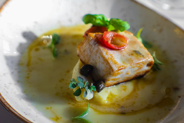 haute cuisine dish with stewed amberjack with mashed potatoes in olive oil, piennolo tomato, taggiasche olives, basil and capers. In a luxurious Italian restaurant - 309278415