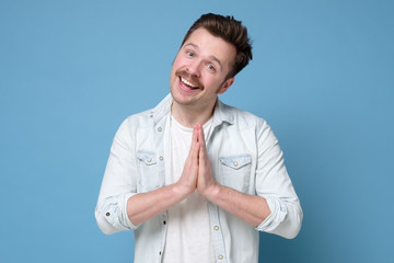 Energized happy man with mustache holding palms together over chest in buddhist namaste gesture