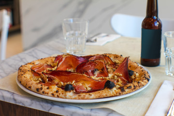 gourmet pizza with casertano pork ham, smoked provola and walnuts paired with craft beer in a typical Italian pizzeria