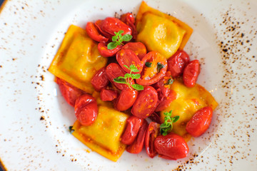 top view of plate of handmade Caprese ravioli served with red corbarino cherry tomato and marjoram - 309278663
