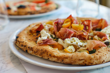 detail of pizza with corbarino yellow tomato, black Casertano pork ham, chopped pistachio and...