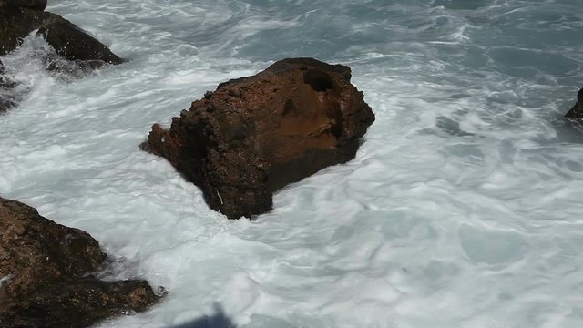 The waves break on the boulders