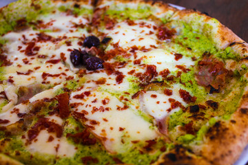 unusual pizza with zucchini cream, olives, ham and bufala mozzarella