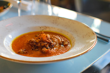 Neapolitan pumpkin soup, very special for its sweet taste, accompanied by fried squid, olive oil and oregano in a luxury Italian restaurant