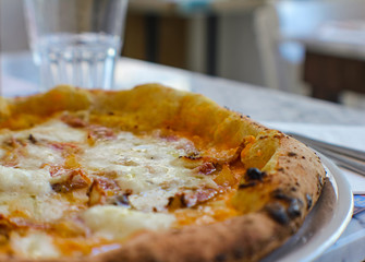 pizzeria table with craft beer with empty label and pumpkin cream pizza, bacon, grated provola and...
