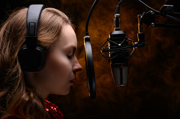 Girl singer sings into a microphone, with a spectacular background, vocals, recording studio,...