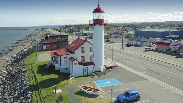 Aerial flying over the Matane Lighthouse, Phare de Matane & highway traffic along the  St Lawrence River. Matane, Gasp&eacute; Peninsula, Quebec, Canada,. 