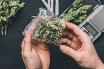 marijuana weed A drug dealer holds a packet of on a dark background top view