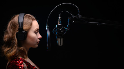 Girl singer sings into a microphone, with a spectacular background, vocals, recording studio,...