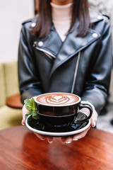 Peppermint mocha coffee. Girl hold cup with latte art.