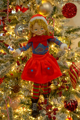 Toy girl Elf,  bright garland  and Christmas decoration hanging on a on the branches of a Christmas tree. Shallow depth of field.  New Year and holiday concept.
