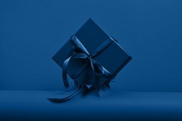 Blue gift box with bow on classic blue paper backround
