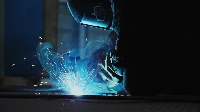 welder welds details on floor at construction site in shop