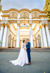 newlyweds stand near an old building with white columns