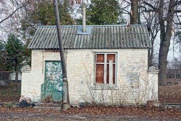 old abandoned white brick house under a gray slate roof on a rural street