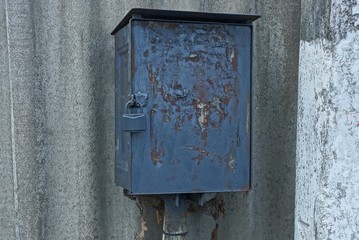 black old iron box for electricity against a gray wall on the street