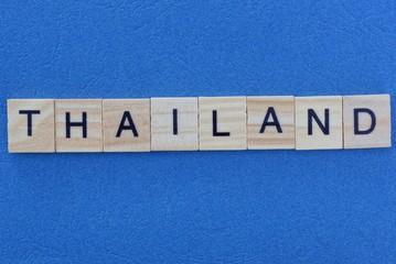 word thailand from wooden gray letters lies on a blue background