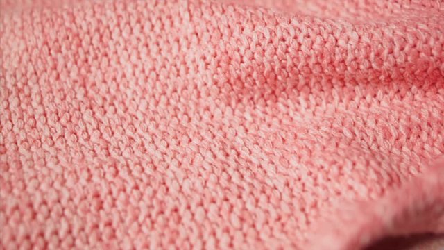Warm and soft acrylic pink or coral fabric, fiber, cloth, sweater. 4k ProRes. Slow pan.