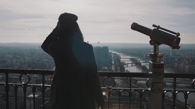 Young beautiful woman on top of Eiffel Tower Paris view panorama walking up to the edge, posing at camera slow motion.