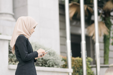 serious expressiong ,portrait of young  business woman with hijab texting someone with her handphone