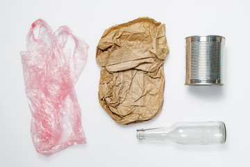 Different types of recyclable garbage. Plastic bag, paper bag, tin can and glass bottle on white...