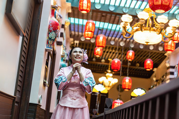 Asian woman in pink traditional chiness dress stand at stair,hand hold together ,feel happy and hope.